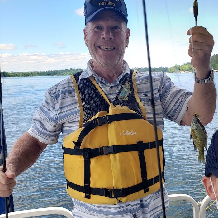 Participant out fishing showing his small catch on his fishing rod! Blue sky with clouds in the background.