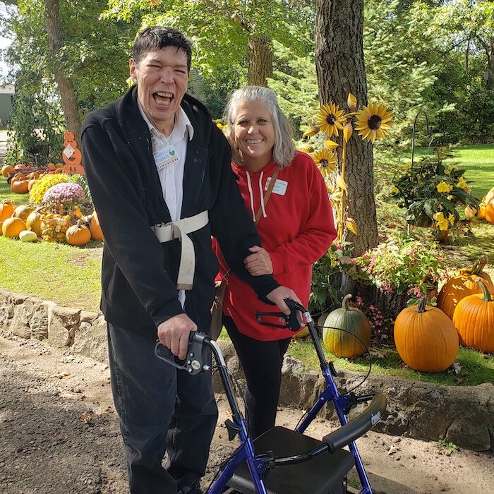 Maxine, staff at BOLADS and participant walking in the pumpkin patch smiling on a sunny day